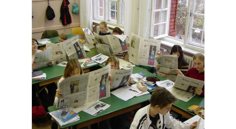zeitungslesende Schüler im Klassenraum