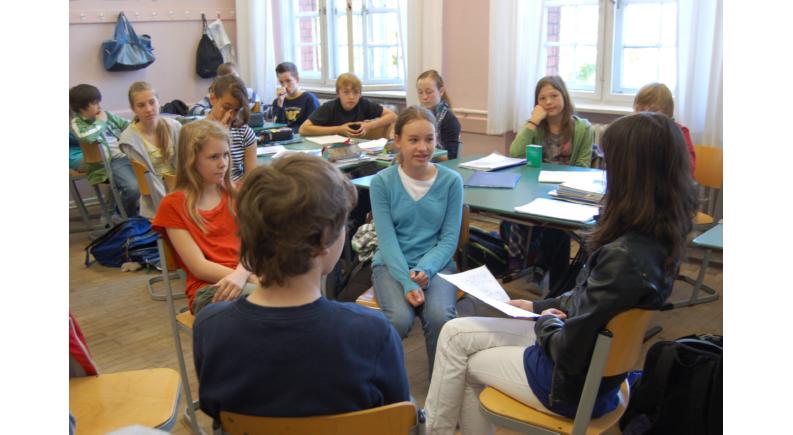 im Kreis sitzende Schülerinnen und Schüler im Klassenraum