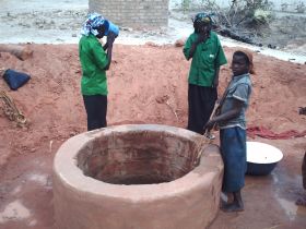 afrikanische Mädchen an einem Lehmbrunnen